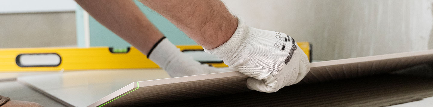 Un ouvrier pose du carrelage sur un plancher chauffant